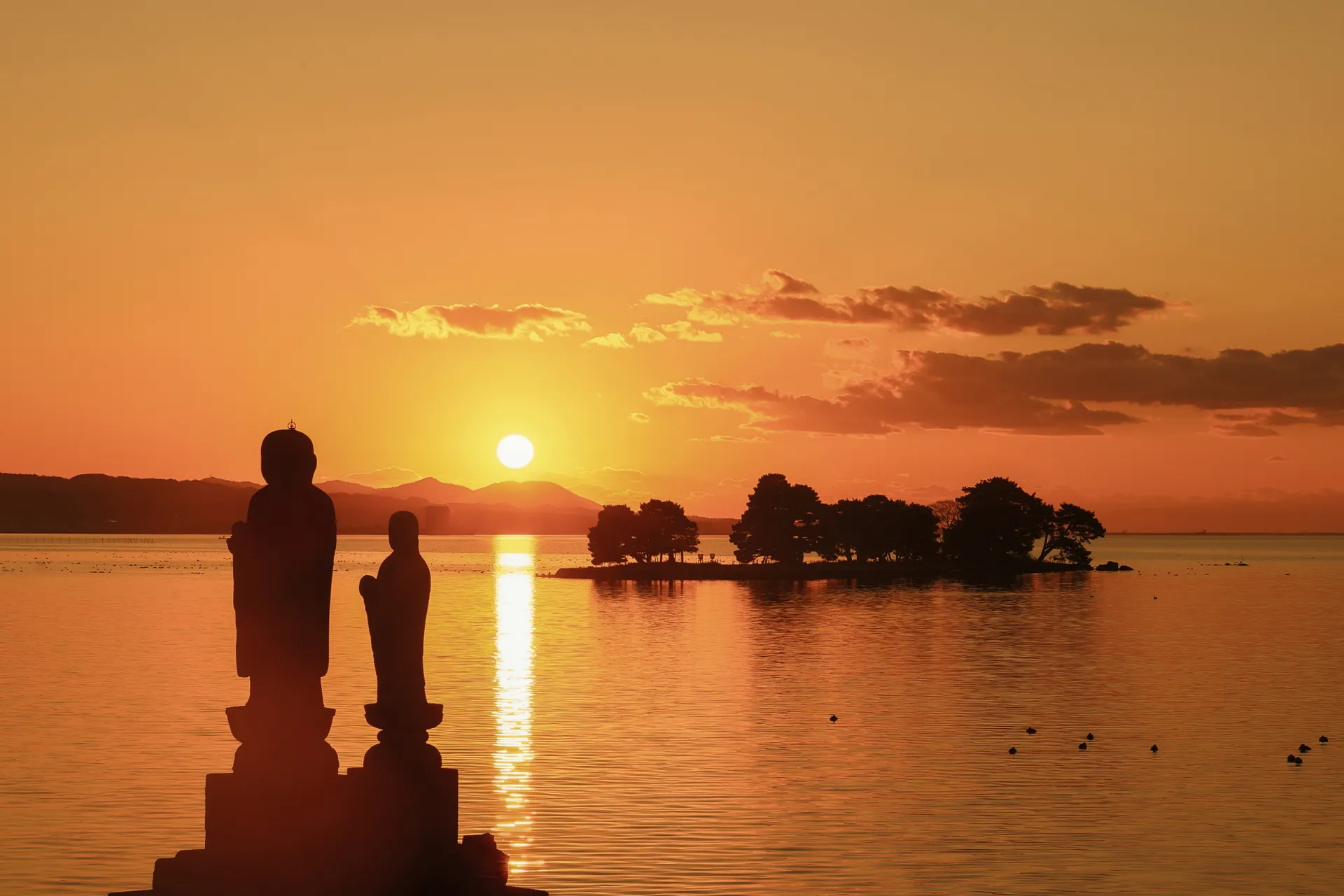 Jizō statues on the shore of Lake Shinji at sunset, with Yomegashima island behind