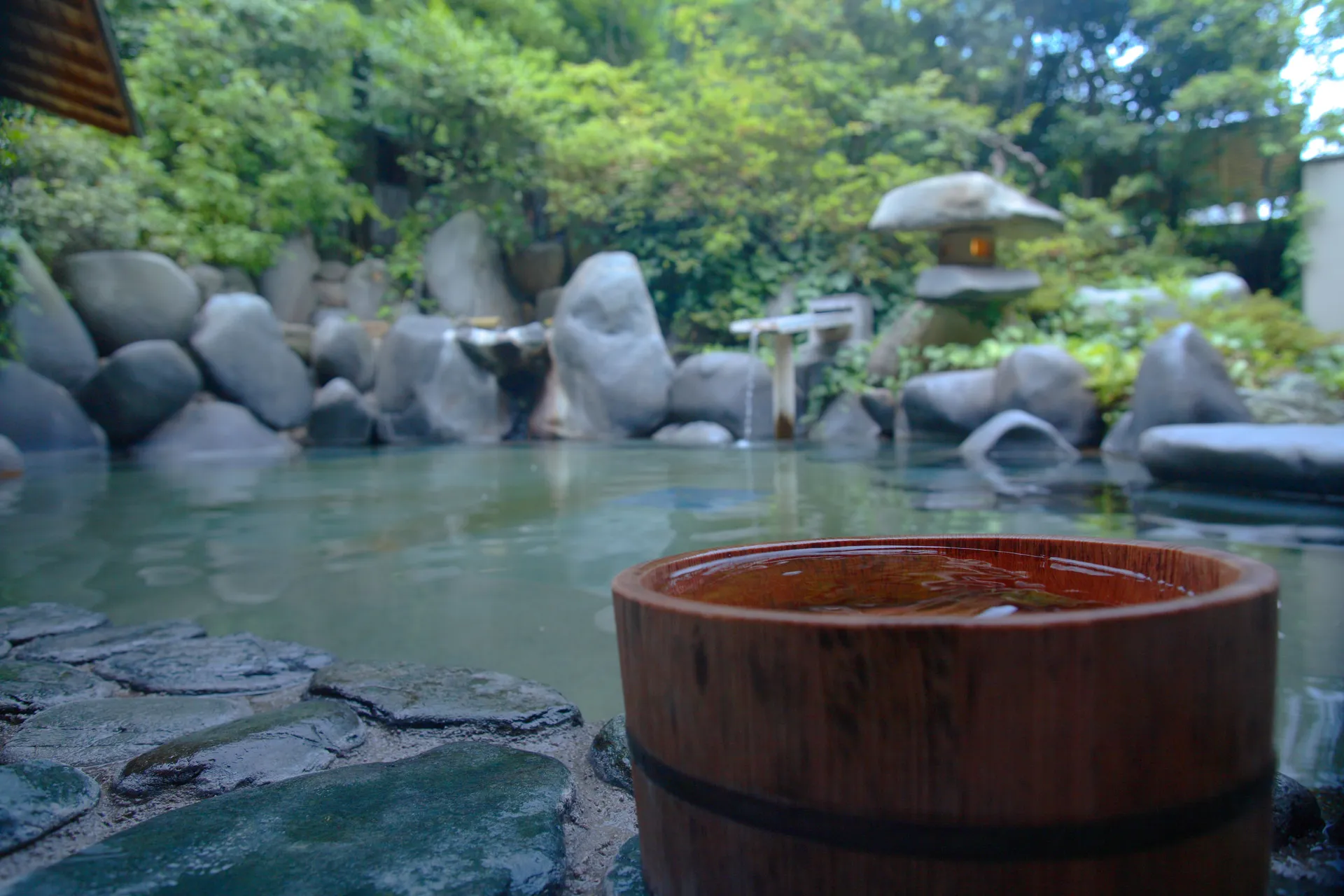 Open-air bath with rocks and a stone lantern in Tamatsukuri Onsen